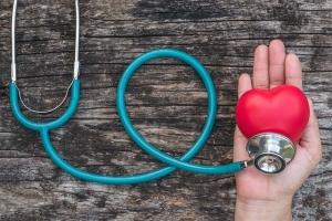 Hand holding heart shaped ball and stethoscope